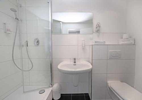 a white bathroom with a sink and a shower at Hotel Brenner in Koblenz