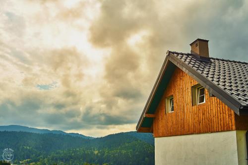 a wooden house with the mountains in the background at Osada Chyże Jewki in Cisna