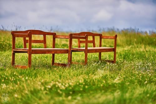 two wooden benches sitting in a field of grass at Osada Chyże Jewki in Cisna