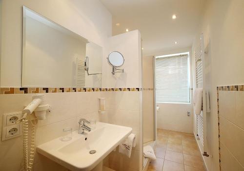 a white bathroom with a sink and a mirror at Hotel Brenner in Koblenz