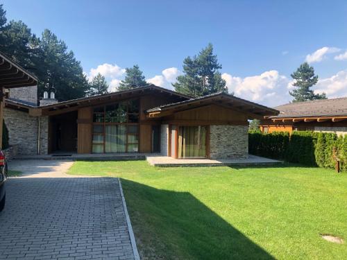 a house with a green lawn in front of it at Pirin Golf and Spa Luxury Chalet in Bansko