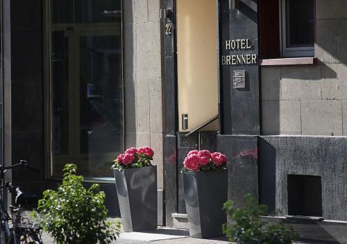 two black containers with flowers in them in front of a hotel at Hotel Brenner in Koblenz