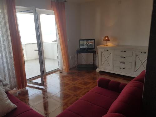 ein Wohnzimmer mit einer roten Couch und einer Glasschiebetür in der Unterkunft Apartments Toni Na Moru in Drage