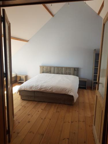 um quarto com uma cama e piso em madeira em Villa Germaine em Stratendries
