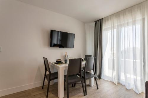 a dining room table with chairs and a tv on the wall at 2NIGHTSTUDIOS in Split