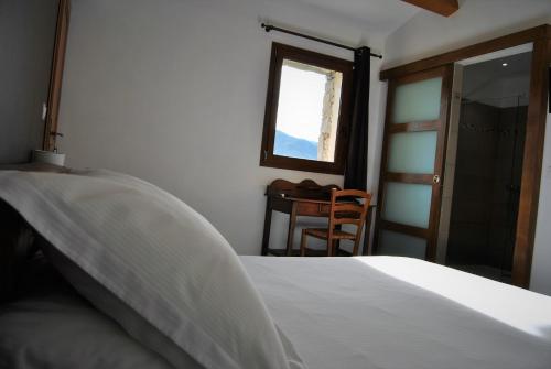 a bedroom with a bed and a window and a table at Maison d'Hôtes Zella in Bains de Guitera