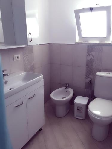 a white bathroom with a sink and a toilet at Eriola apartament in Orikum