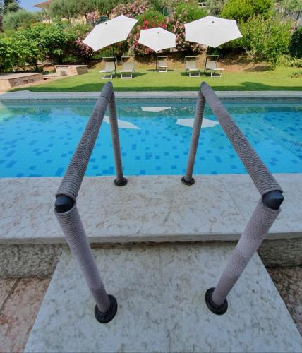 a swimming pool with two umbrellas in front of it at B&B - Relais de charme la Caminella in San Pietro in Cariano