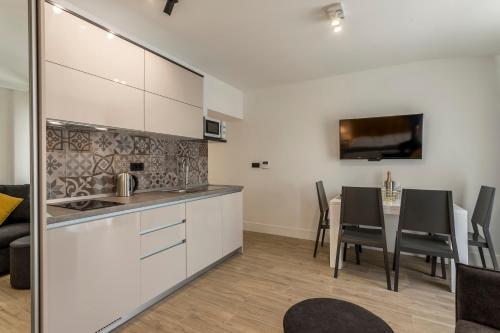 a kitchen with white cabinets and a table with chairs at 2NIGHTSTUDIOS in Split
