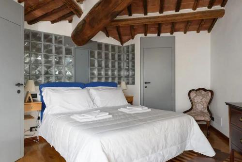 a bedroom with a large white bed and a chair at Penthouse in Siena near Piazza del Campo in Siena