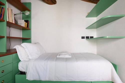 a bedroom with a white bed and green shelves at Penthouse in Siena near Piazza del Campo in Siena