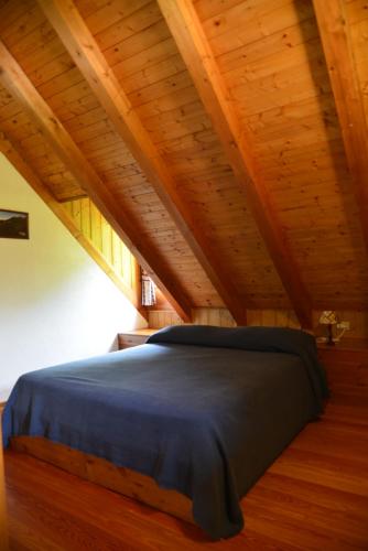 a bed in a room with a wooden ceiling at Agriturismo Pian dei Tass in Barcis