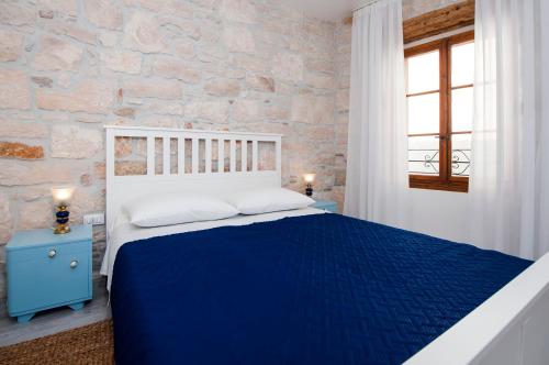 a bedroom with a blue bed and a stone wall at Apartment Babbo in Rovinj