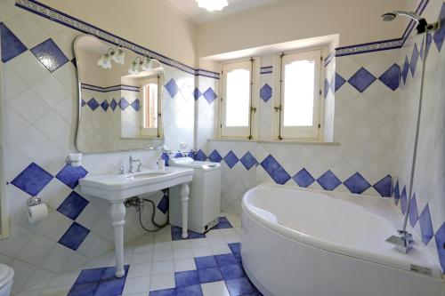 伊斯皮卡的住宿－Eremo delle Grazie，蓝色和白色的浴室设有浴缸和水槽