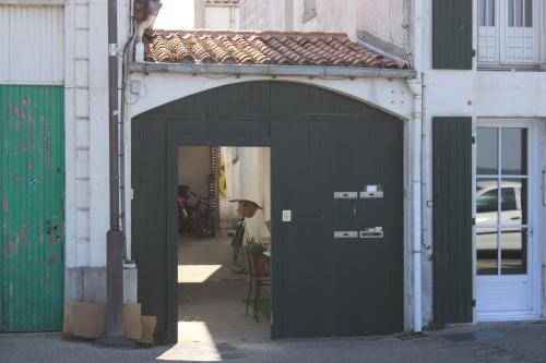 ein Torbogen mit einer schwarzen Tür auf einem Gebäude in der Unterkunft COUP DE COEUR Studio in Rivedoux-Plage