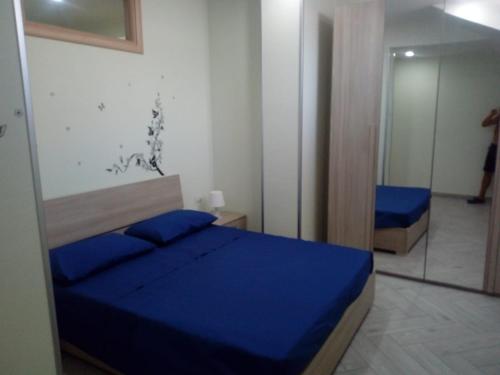 a bedroom with a blue bed and a mirror at Appartamento in Residenza Punta di Sabaudia - seminterrato in Sabaudia