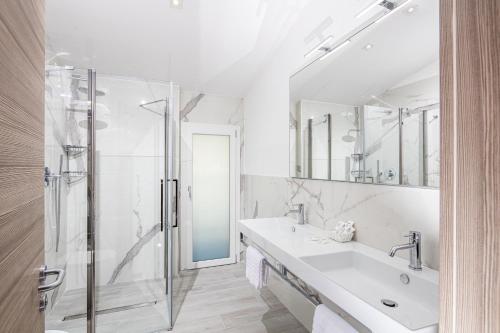 uma casa de banho com uma cabina de duche em vidro e um lavatório. em Hotel Capitol em Lido di Jesolo
