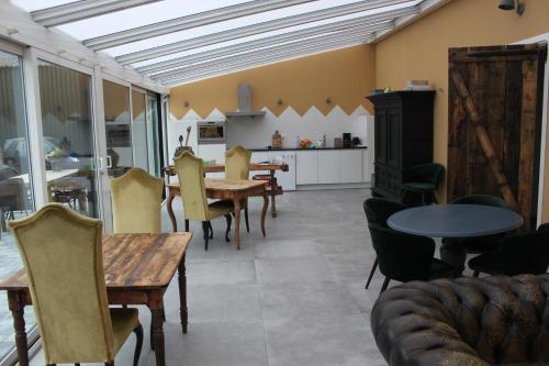 uma sala de estar com mesas e cadeiras e uma cozinha em B&B de Sfeerhoeve em Beilen