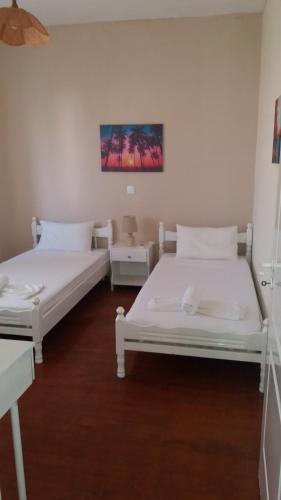 two beds in a room with white walls and wooden floors at Pitsinis Apartments II in Roda