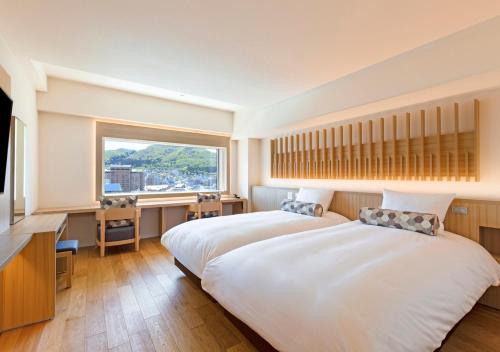 a bedroom with two beds and a large window at HOTEL＆SPA CENTURY MARINA HAKODATE in Hakodate