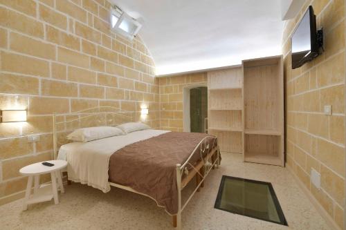 ein Schlafzimmer mit einem Bett in einer Ziegelwand in der Unterkunft I Battenti in Galatina