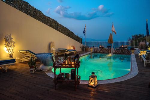 una piscina con terraza con mesa y sillas en Castri Village Kythira Quality Resort, en Agia Pelagia - Citera