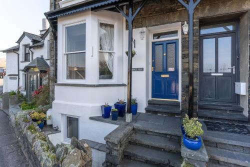 a house with a blue door and some potted plants at Barnes Fell Apartments in Ambleside