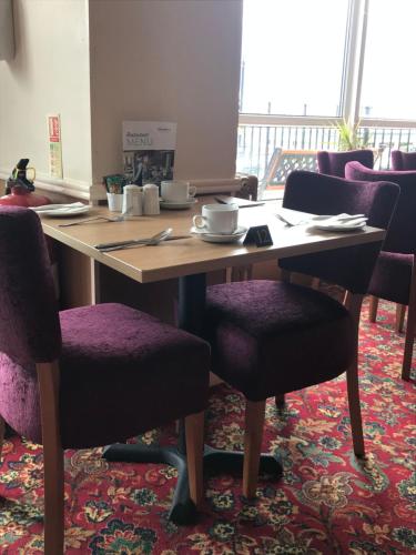 a wooden table with chairs and a laptop on it at Monarch Hotel in Bridlington