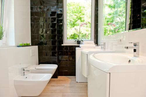 a white bathroom with a sink and a toilet at Bursztynowa Zatoka BlueApart Jurata in Jurata