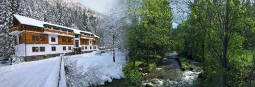 a building with snow on the ground next to a river at Riverside in Demanovska Dolina
