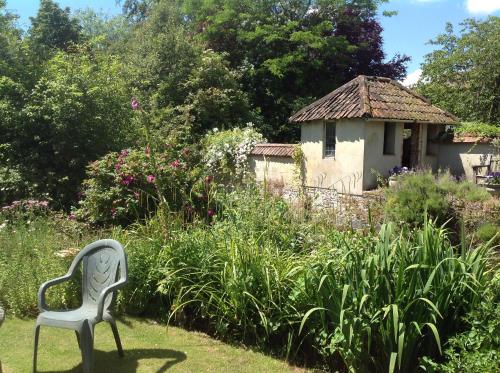 a white chair sitting in the middle of a garden at The Mill House in Berwick Saint James