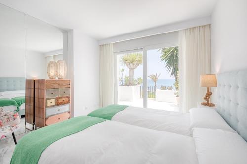ein weißes Schlafzimmer mit einem Bett und einem großen Fenster in der Unterkunft Hanami Alcazaba Beach Front Sea View in Estepona