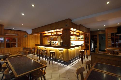 a bar in a restaurant with tables and chairs at Hotel Restaurant Le Giétroz in Le Châble