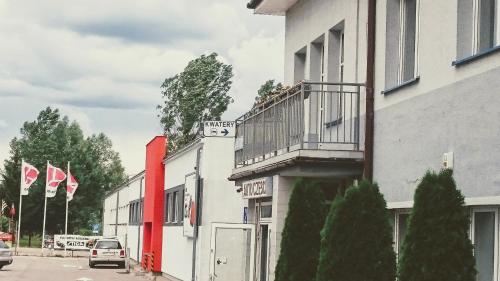 a building with a balcony and flags on a street at Kwatery w Gołdapi in Gołdap