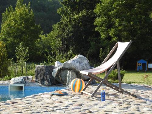 a chair and a ball sitting next to a pool at Exo Log Cottage in Jezero