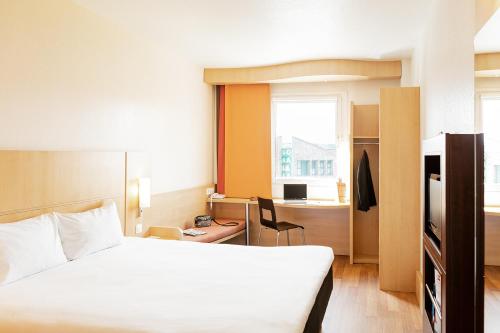 オビエドにあるIbis Oviedoのベッド、デスク、窓が備わるホテルルームです。