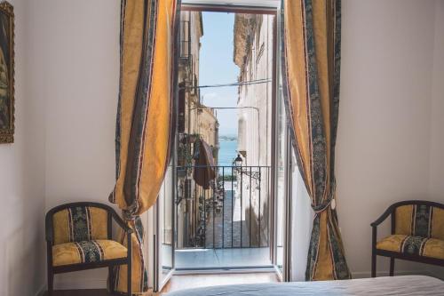 a bedroom with a view of a city from a window at Suites of the Royal Council in Siracusa