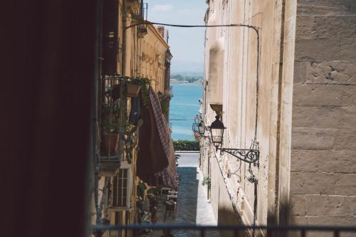 an alleyway between buildings with a view of the ocean at Suites of the Royal Council in Siracusa