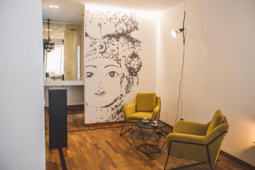 a living room with two chairs and a drawing on the wall at Suites of the Royal Council in Siracusa