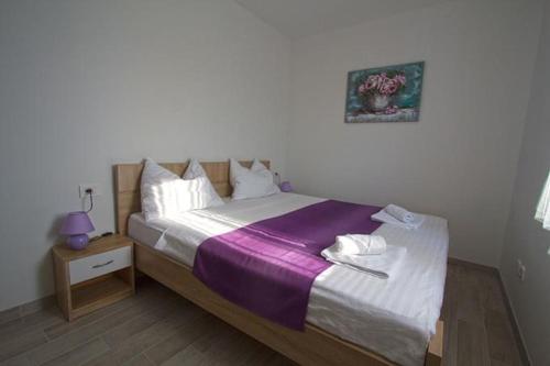 um quarto com uma cama grande e um cobertor roxo em Apartment Annabella with Pool and sea view em Karlobag