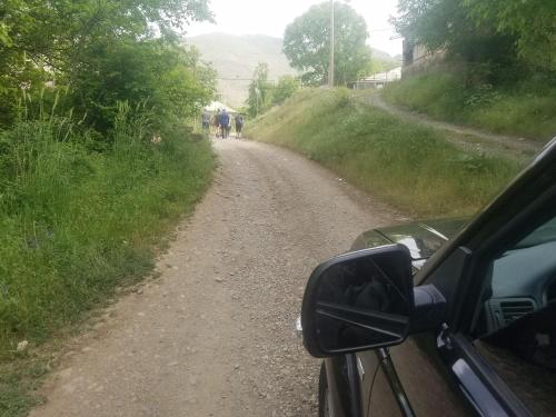 a car on a dirt road with people walking down it at Karine B&B in Yeghegnadzor