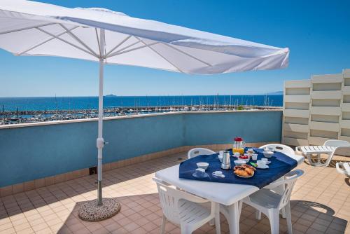 un tavolo con cibo e ombrellone su un balcone di Residence Marina Salivoli a Piombino