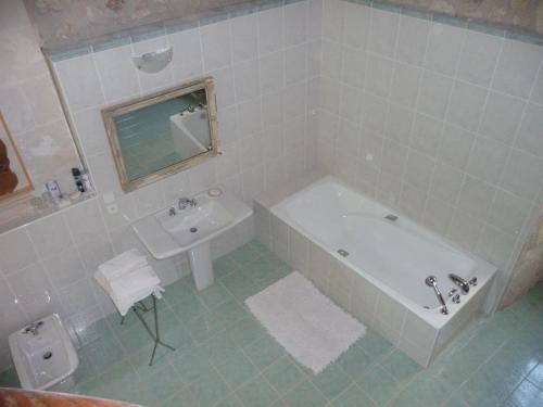 a white bathroom with a tub and a sink at Le Claveau in Paulnay