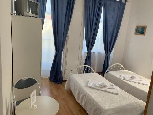 リスボンにあるレジデンシア ホワイトラブのベッド2台、青いカーテン付きの窓が備わる客室です。