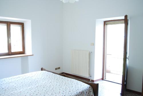 a white bedroom with a bed and two windows at Casa rosa sull'appennino tosco emiliano in Barigazzo