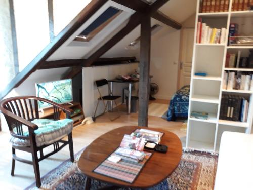 een woonkamer met een tafel en een stoel bij Vacances Paisibles Sur La Côte Fleurie. in Trouville-sur-Mer