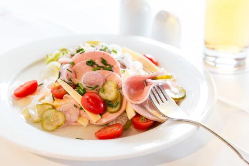 a bowl of pasta with meat and vegetables with a fork at Hotel Hörterer Der Hammerwirt in Siegsdorf