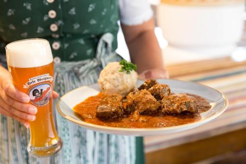 a person holding a plate of food and a glass of beer at Hotel Hörterer Der Hammerwirt in Siegsdorf