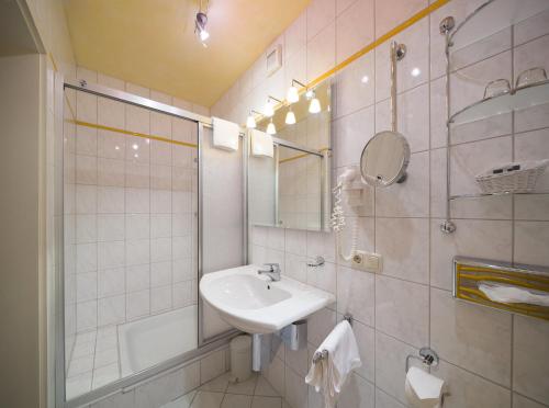 a white bathroom with a sink and a mirror at Hotel Hörterer Der Hammerwirt in Siegsdorf
