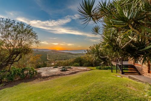 a bench on a grassy hill with the sunset in the background at Ulwazi Rock Lodge in Hazyview